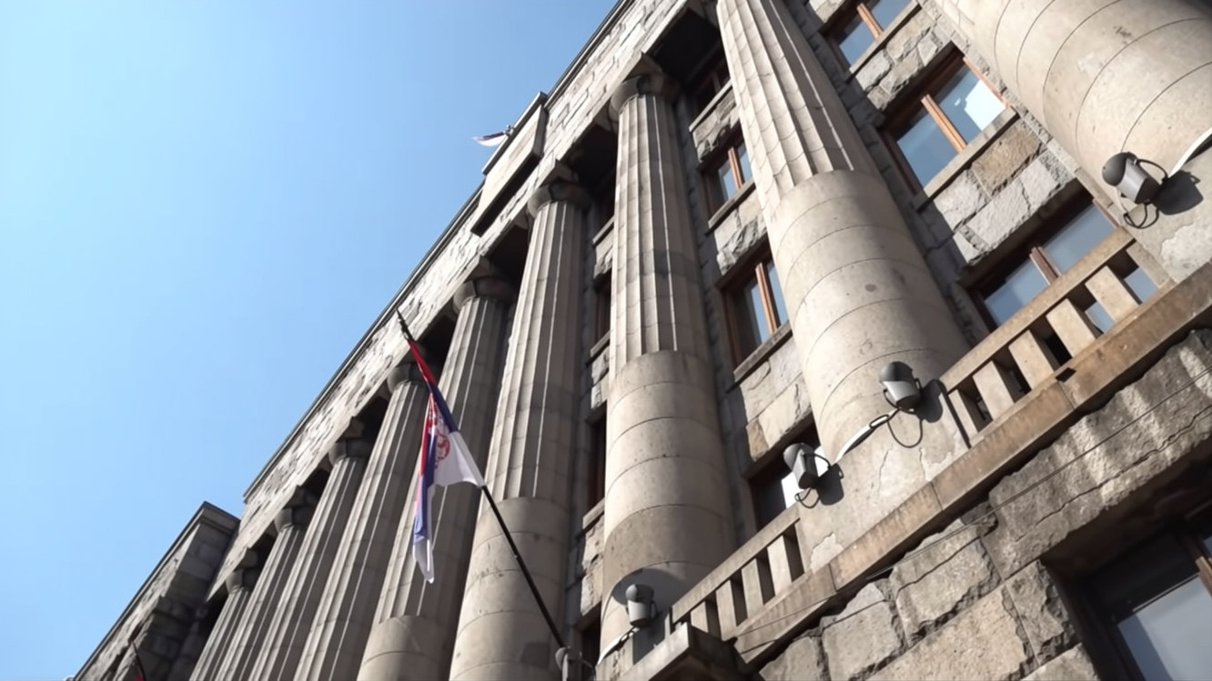 Fasada državne institucije u Srbiji sa visokim stubovima i zastavom ispred zgrade.