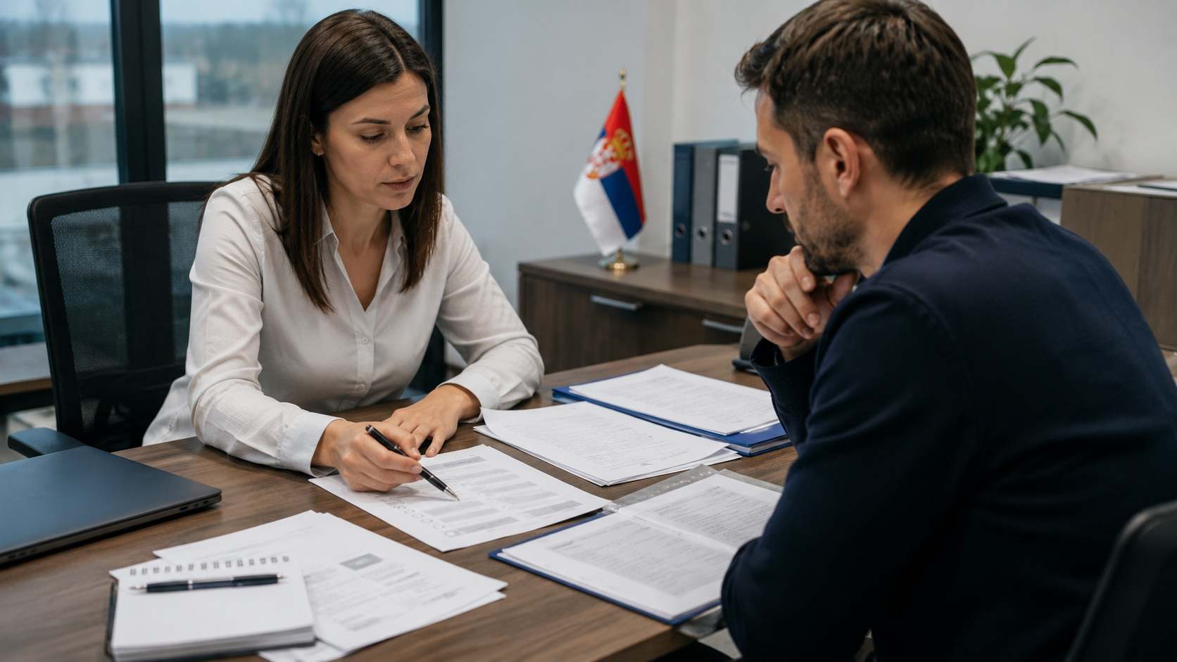 Žena u kancelariji pokazuje dokumente muškarcu tokom pripreme pritužbe zbog diskriminacije.